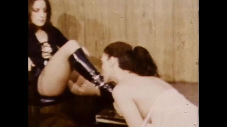 Vintage megastore: Dominatrix lesbiana en vestido de cuero y botas negras dominando...